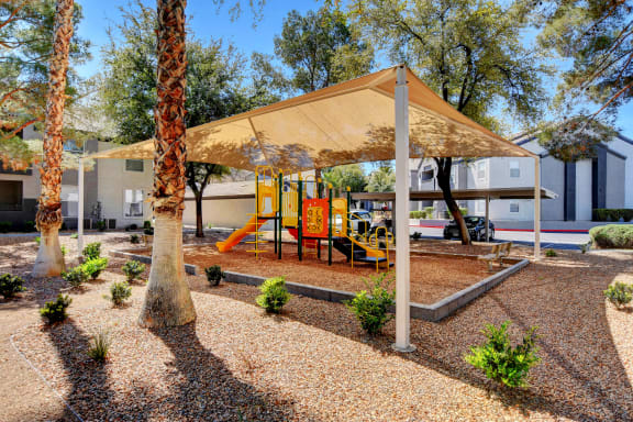 Shaded playground with jungle gym and slide