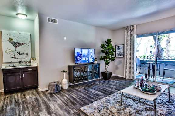 Livingroom with wood like style flooring, TV stand, TV, area rug, coffee table and curtains.