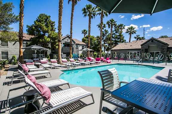 Pool desk with lounge chairs surround the pool and the club house in the background.