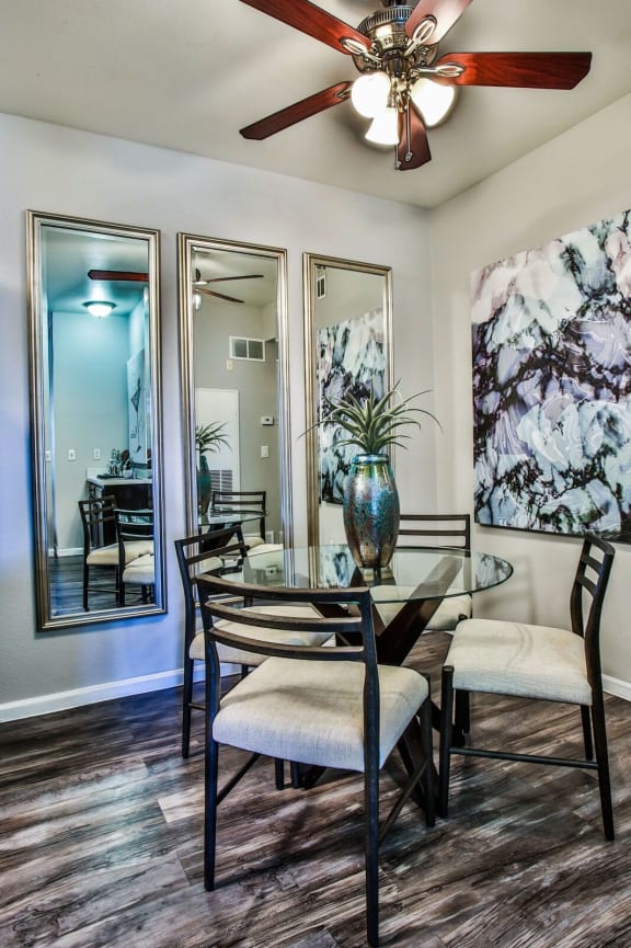 Dining area with table and chairs, wall art and wood like style flooring.