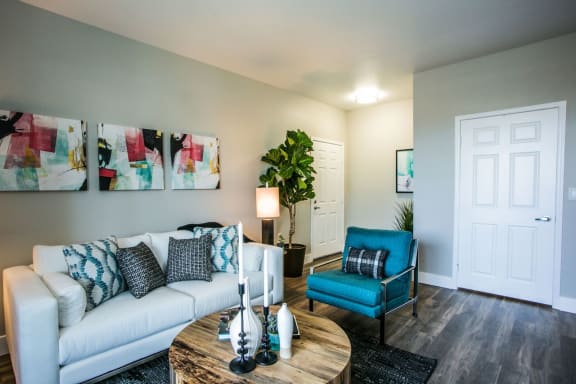 Livingroom with couch, arm chair, area rug, coffee table, wall art, end table, table lamp and wood like style flooring.