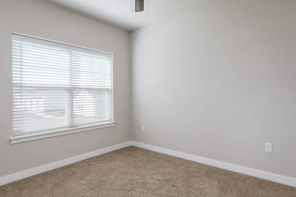 a bedroom with a large window and a carpeted floor