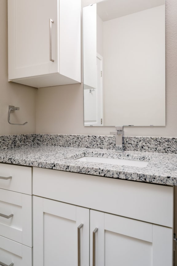 a bathroom with white cabinets and granite countertops