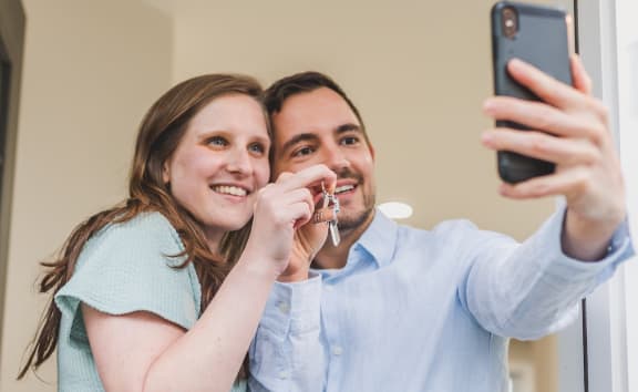 Happy Couple taking a selfie with keys to their new apartment