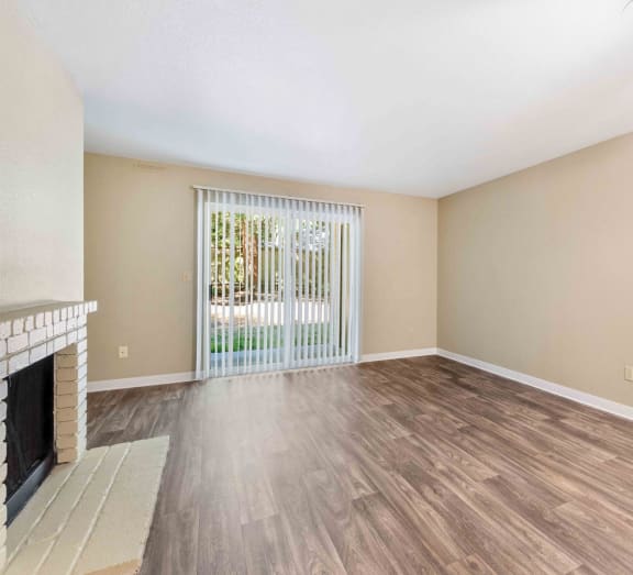 the spacious living room with a fireplace and wood flooring