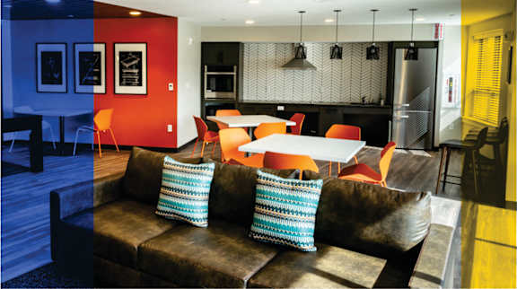 A living room with a brown couch and a red wall.