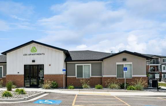 A parking lot in front of a building with the sign "LEX Apartments" on it.