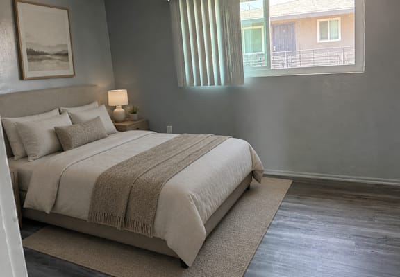 A bedroom with a bed, lamp, and a painting on the wall.