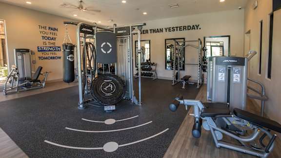 A gym with a variety of equipment and a motivational quote on the wall.