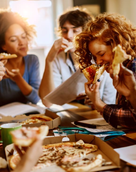 a group of people sitting around a table eating pizza