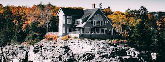 A house is built on a rocky outcrop by the water.