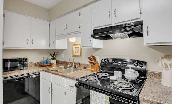 A kitchen with a black stove top oven and white cabinets.