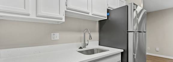 A kitchen with a black refrigerator and white cabinets.