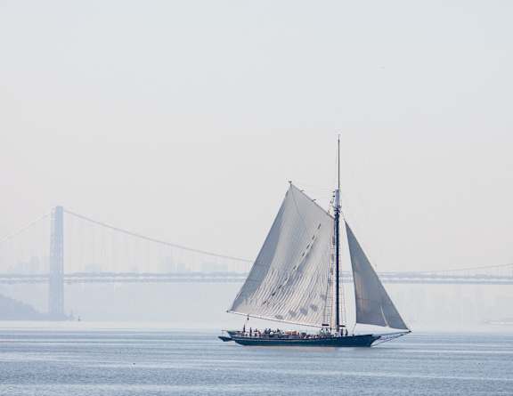 a sailboat on the water with a bridge in the background