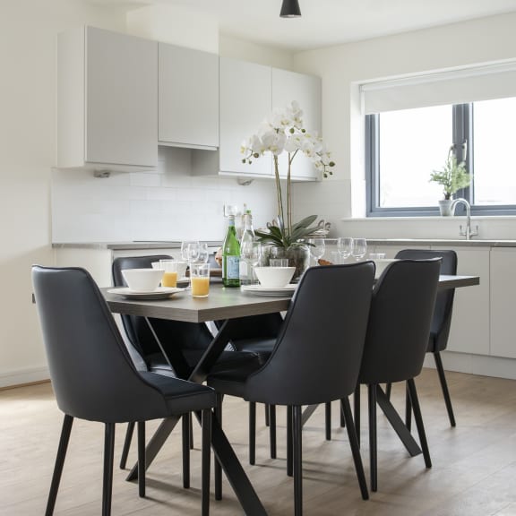 a kitchen with white cabinets and a table with black chairs
