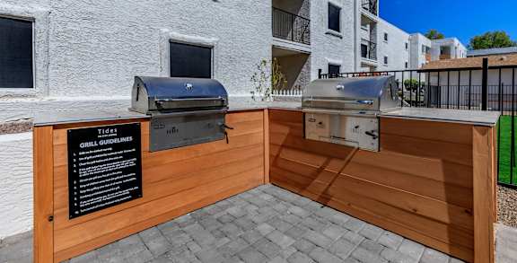 bbq area with two grills in front of an apartment building