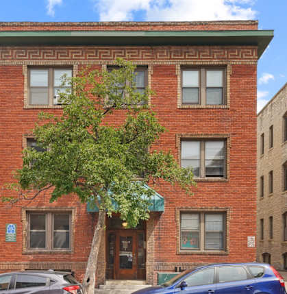 A red brick building with a tree in front of it.