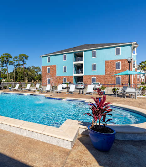 A pool surrounded by chairs and a building in the background.