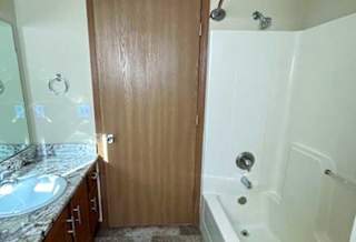 a bathroom with a tub shower, sink, and mirror