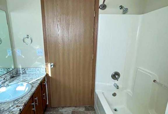 a bathroom with a tub shower, sink, and mirror