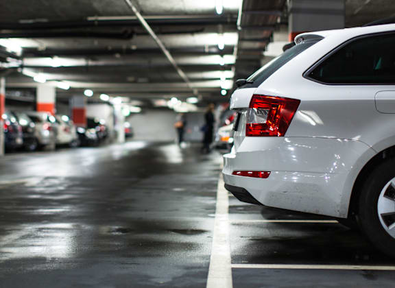 A white car is parked in a dimly lit parking garage.