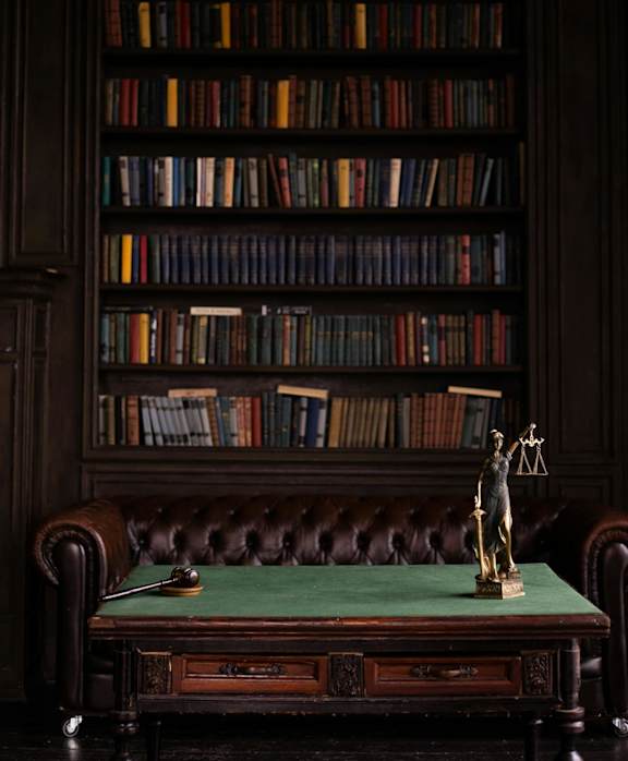 a statue on a desk in front of a book shelf