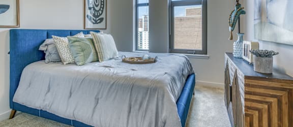 a bedroom with a bed and a dresser and three windows