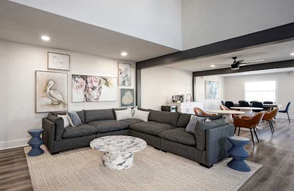 A living room with a grey sofa and a round marble table.