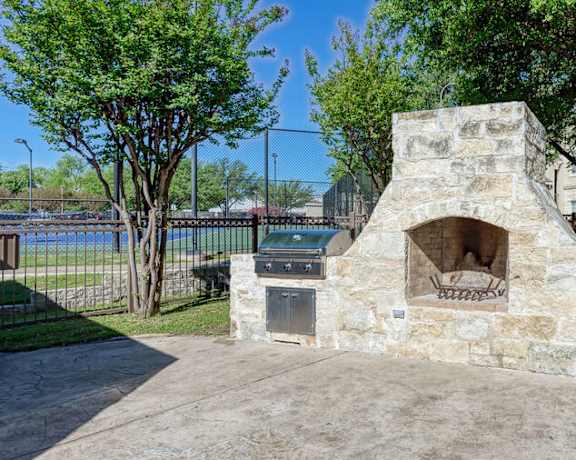 stone fire pit with two grills in gated area