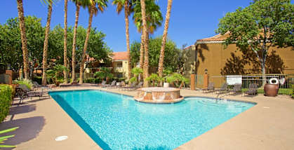 A swimming pool surrounded by palm trees and lounge chairs.