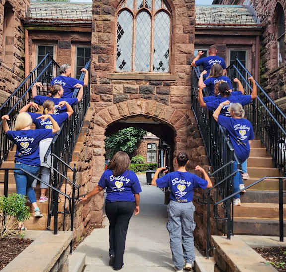 A group of people in blue shirts are walking up a set of stairs.