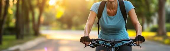 A woman is riding a bicycle on a tree-lined street.