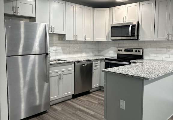 A modern kitchen with stainless steel appliances and white cabinetry.