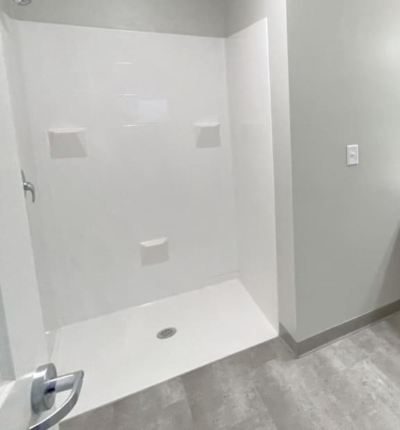 A white shower stall with a white seat and a white bench.