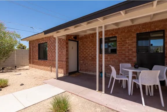 A patio with a table and chairs is in front of a brick house.