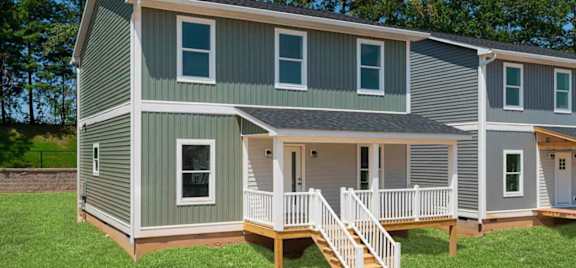 Charlotte model home at Belle Meadow in Asheville with green and gray siding, covered porch, and white railings.