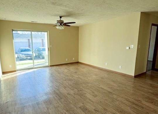 a living room with hardwood flooring and a ceiling fan