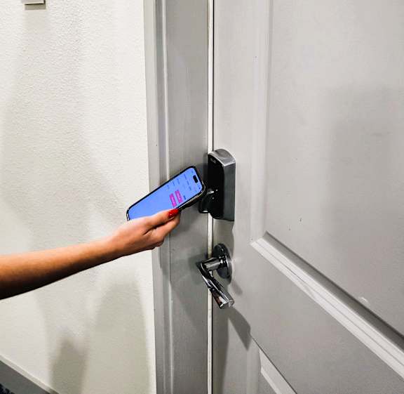 A hand is holding a phone up to a door handle.