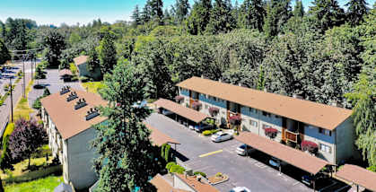 A parking lot in front of a building surrounded by trees.
