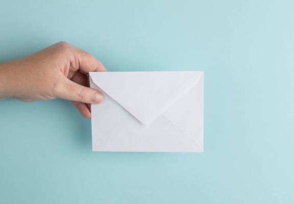a hand holding a white envelope on a blue surface