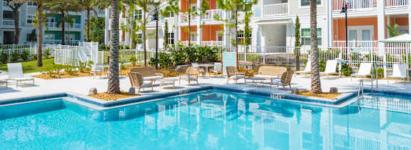A pool surrounded by palm trees and lounge chairs.