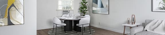 a living and dining room with white walls and a wood floor