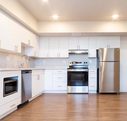 A modern kitchen with white cabinets and stainless steel appliances. at All Saints Apartments, DENVER, Colorado