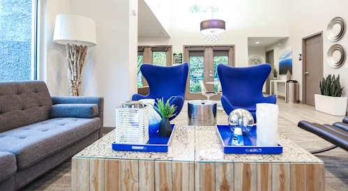 A living room with a grey couch, a wooden coffee table, and blue chairs.