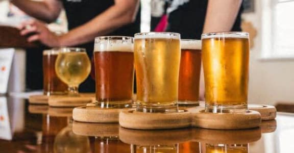 a row of glasses of beer on a table