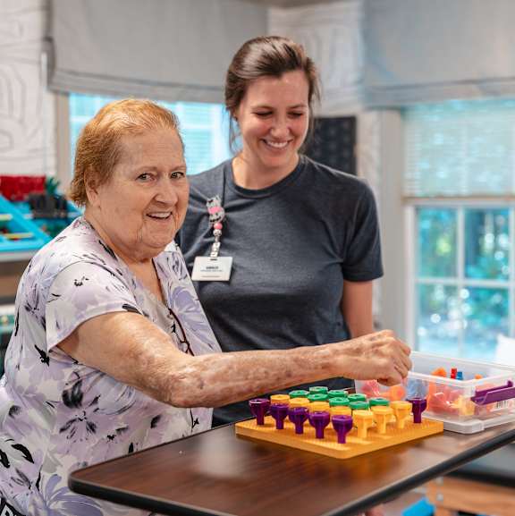 An elderly woman playing a board game with a younger woman.