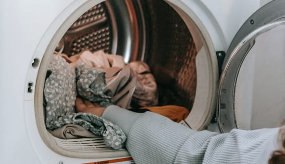 a woman putting a pile of laundry into a washing machine