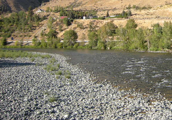 A river flows through a valley with a hill in the background.