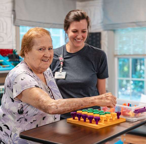 An elderly woman playing a board game with a younger woman.
