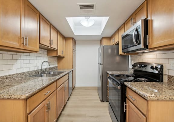 A kitchen with wooden cabinets and granite countertops.
